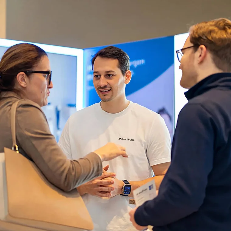 A conversation at the MediPulse stand: a team member talking with two visitors